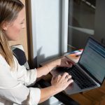 woman in white long sleeve shirt using black laptop computer