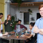 Man Standing Beside People Sitting Beside Table With Laptops