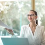 New Mexico Tax ID (EIN) Number Application Online & Manual Low angle of successful female executive manager in classy style sitting at table with laptop in contemporary workplace and passing documents to colleague