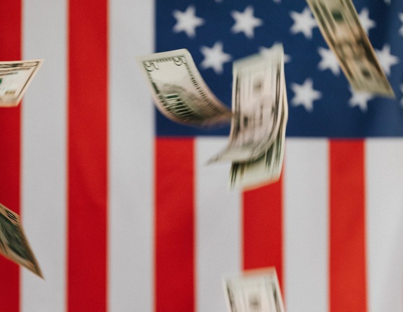 National flag of United States of America on background and dollars falling down