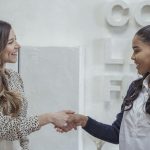 Cheerful multiethnic businesswomen shaking hands in modern office