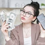A Woman holding Smartphone and Money