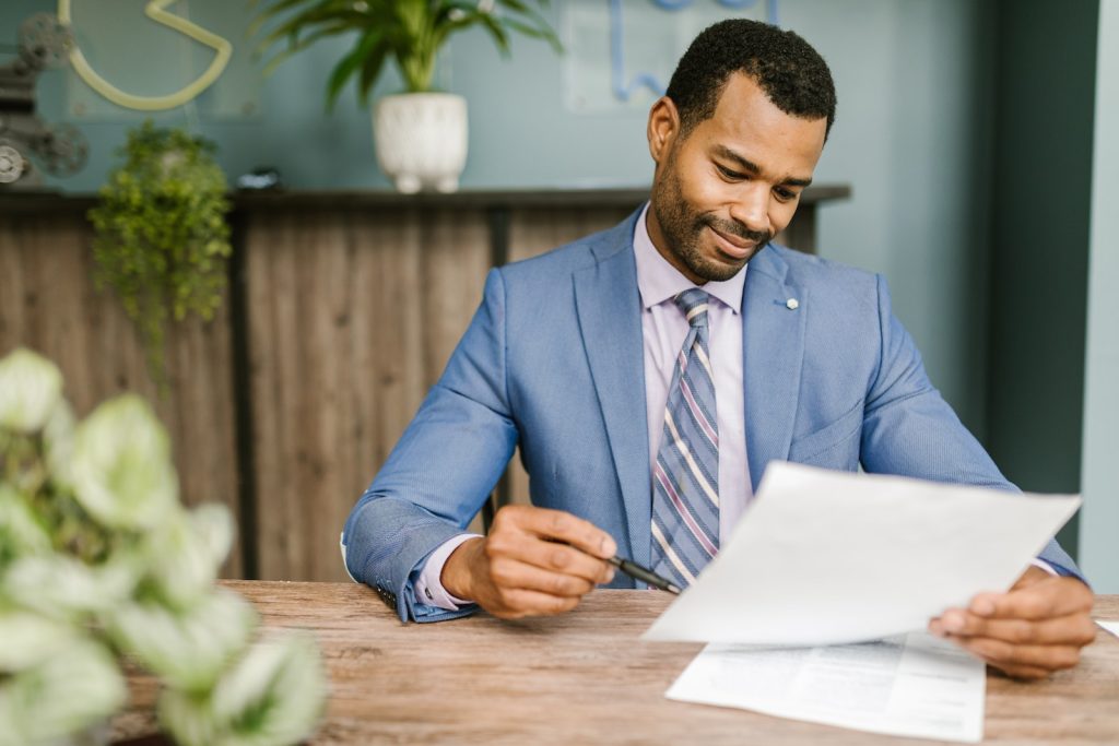 Man in Blue Suit Jacket Holding White Paper and Ballpen