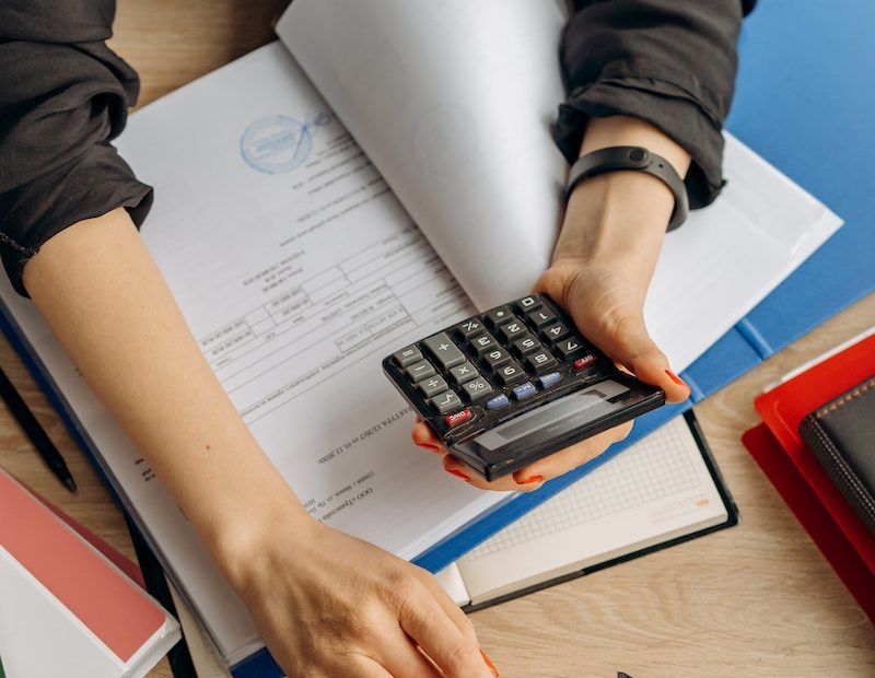 Person Holding Black Calculator While Using Laptop