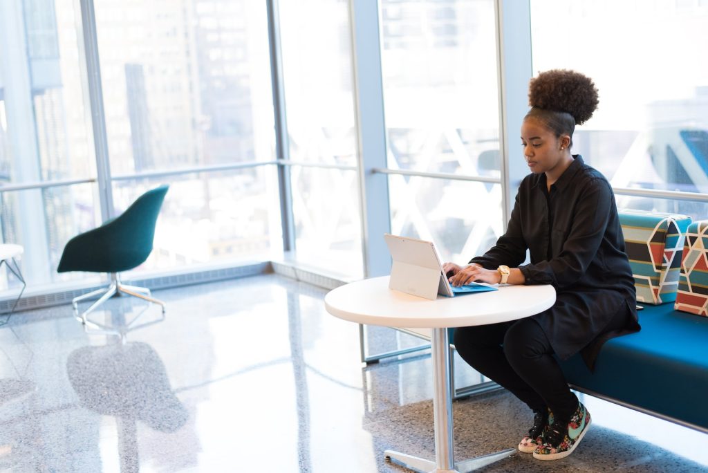 woman sits of sofa while using tablet computer